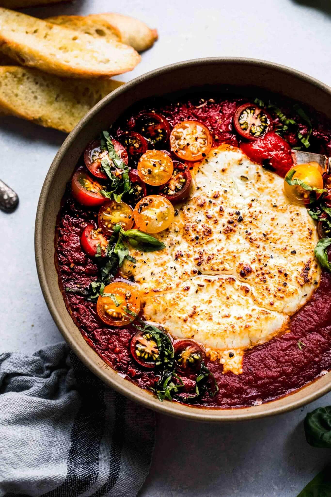 This baked goat cheese dip is a super simple appetizer recipe that's easy to throw together at the last minute with just 3 ingredients! Chevre is baked in marinara sauce until hot and bubbly – Perfect for spreading on crostini.