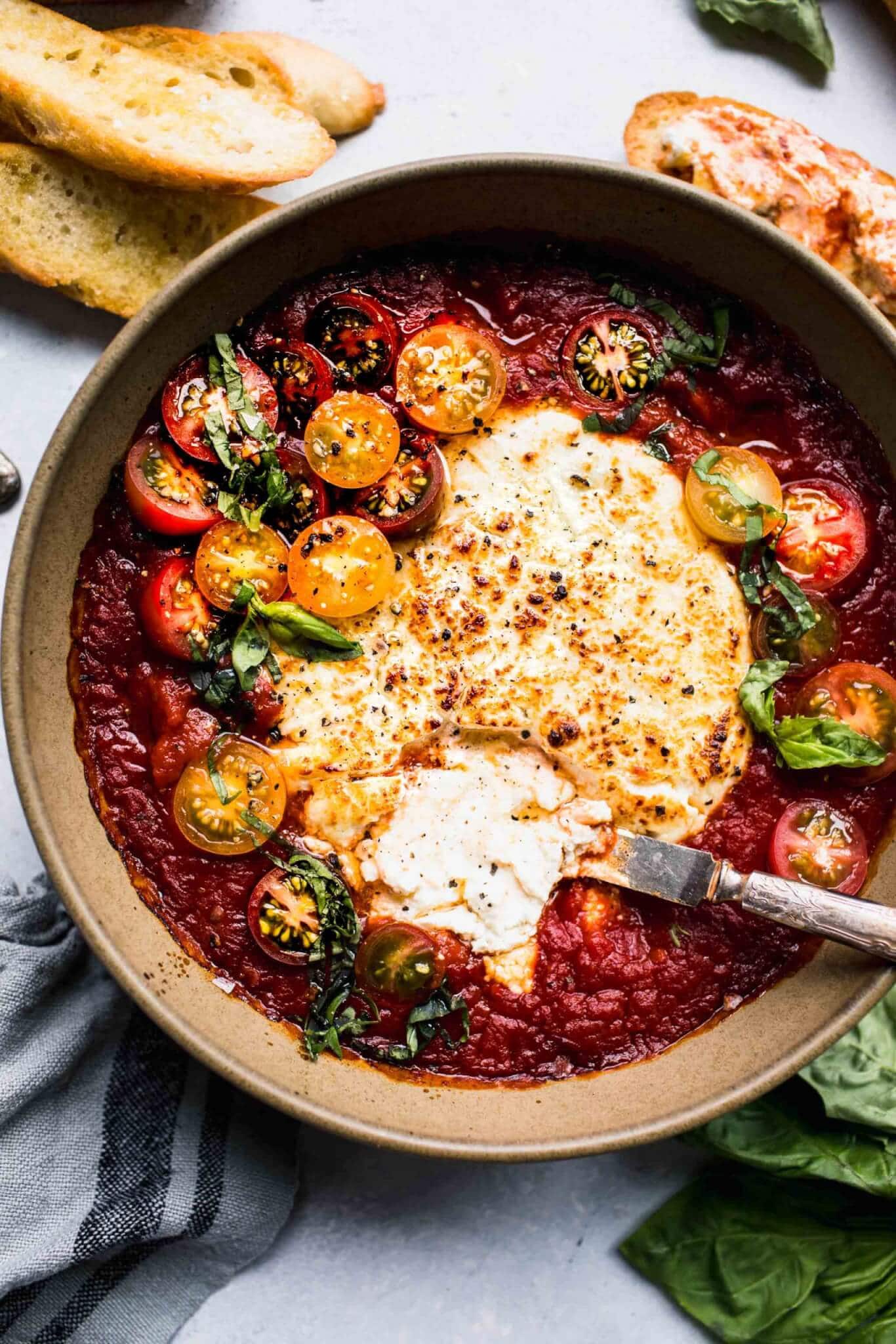 This baked goat cheese dip is a super simple appetizer recipe that's easy to throw together at the last minute with just 3 ingredients! Chevre is baked in marinara sauce until hot and bubbly – Perfect for spreading on crostini.