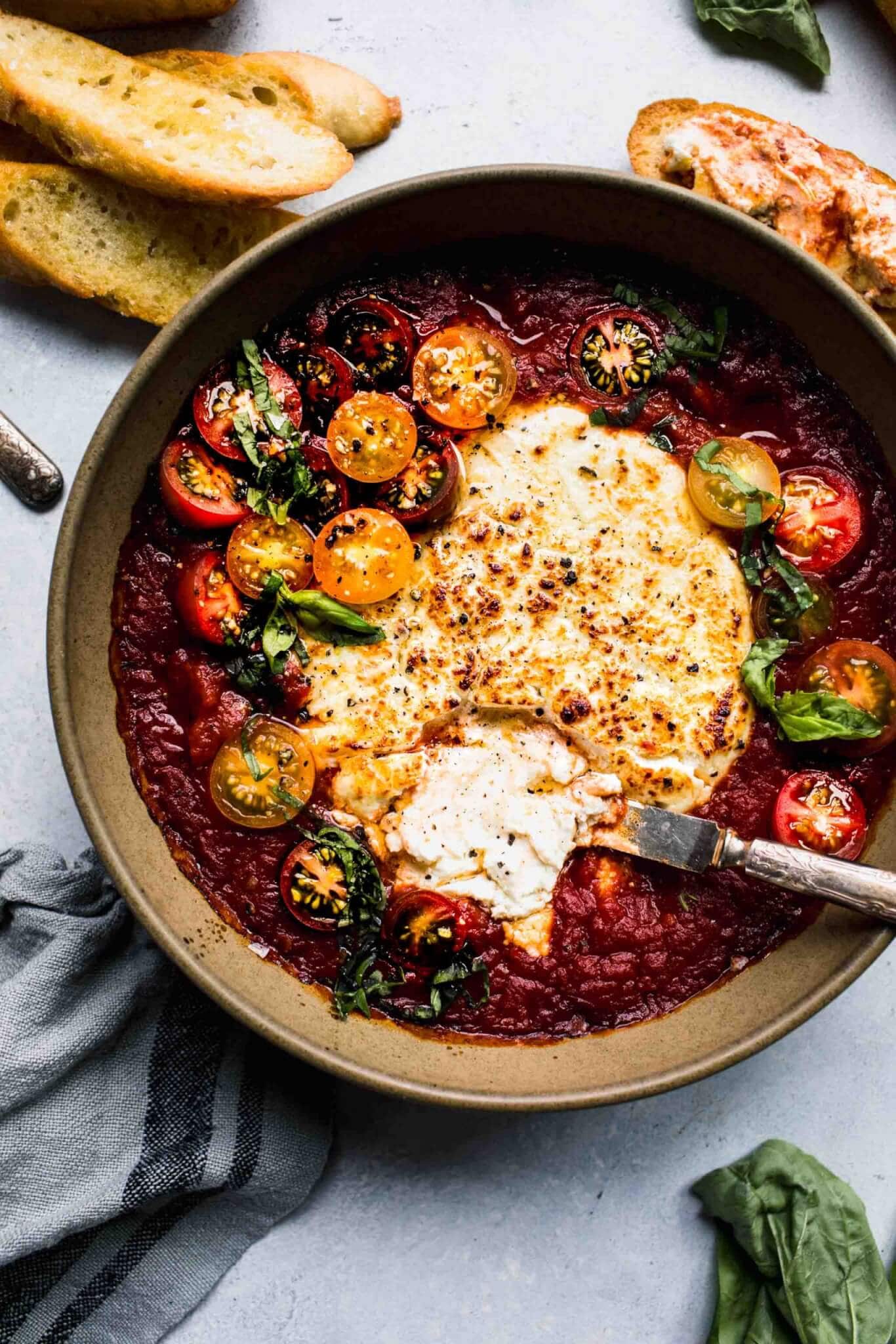 Bowl of baked goat cheese with tomatoes.