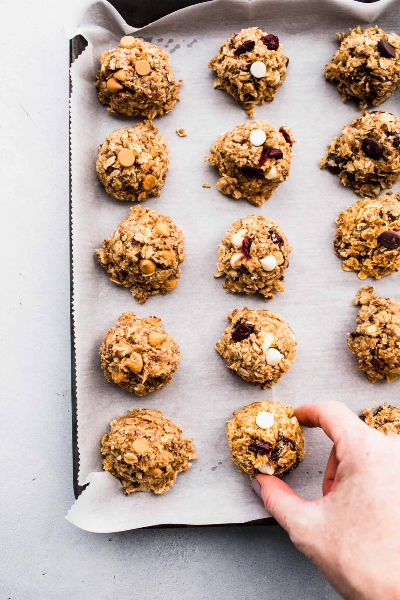 Hand picking up no-bake energy bite from cookie sheet
