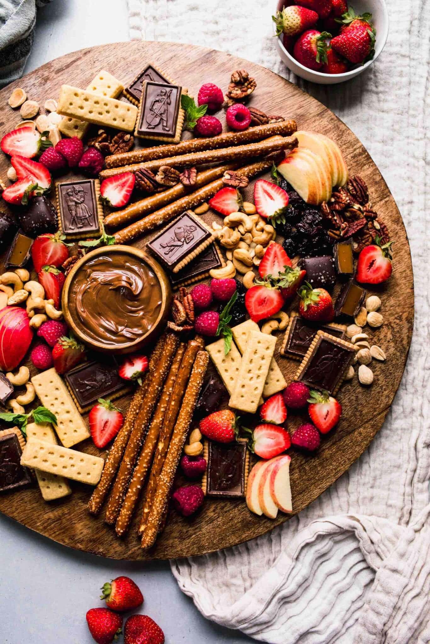 Dessert chocolate board next to small bowl of strawberries. 