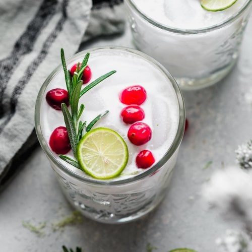 Overhead view of two holiday margaritas with cranberries and lime.