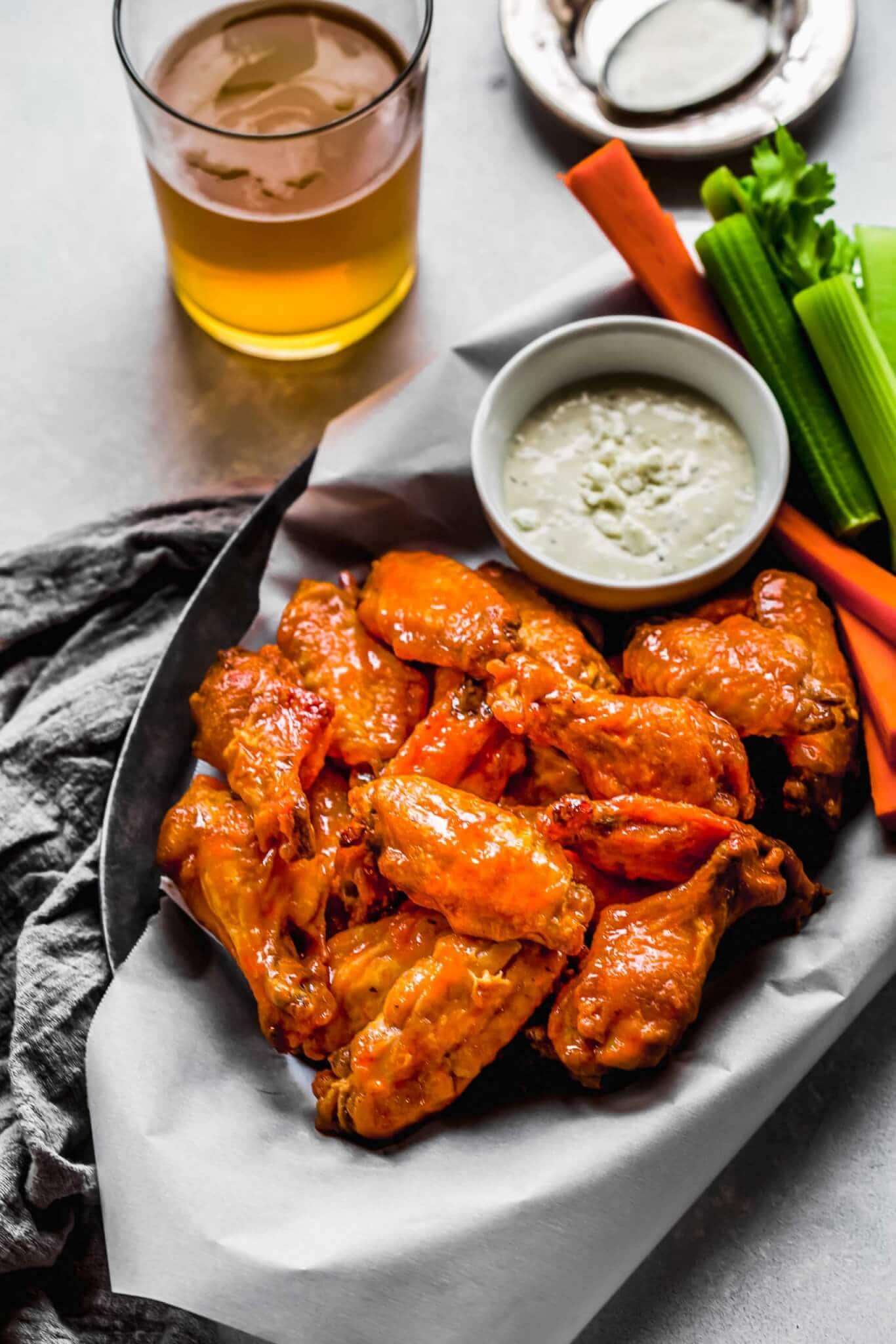 Side view of Air fryer wings in serving basket with blue cheese and celery sticks.