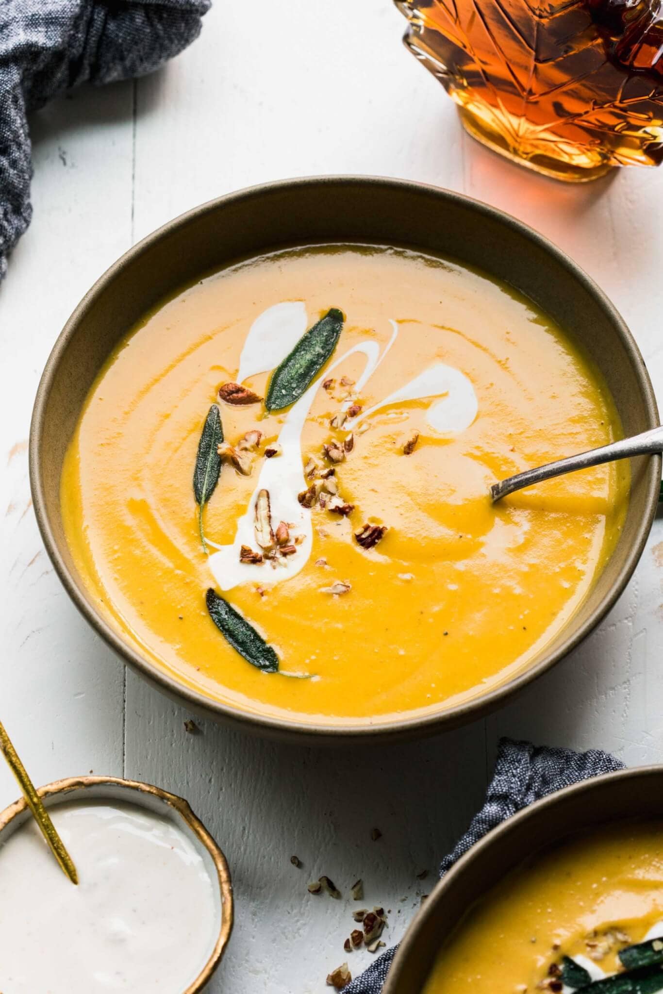 Bowl of butternut squash bisque topped with sage leaves