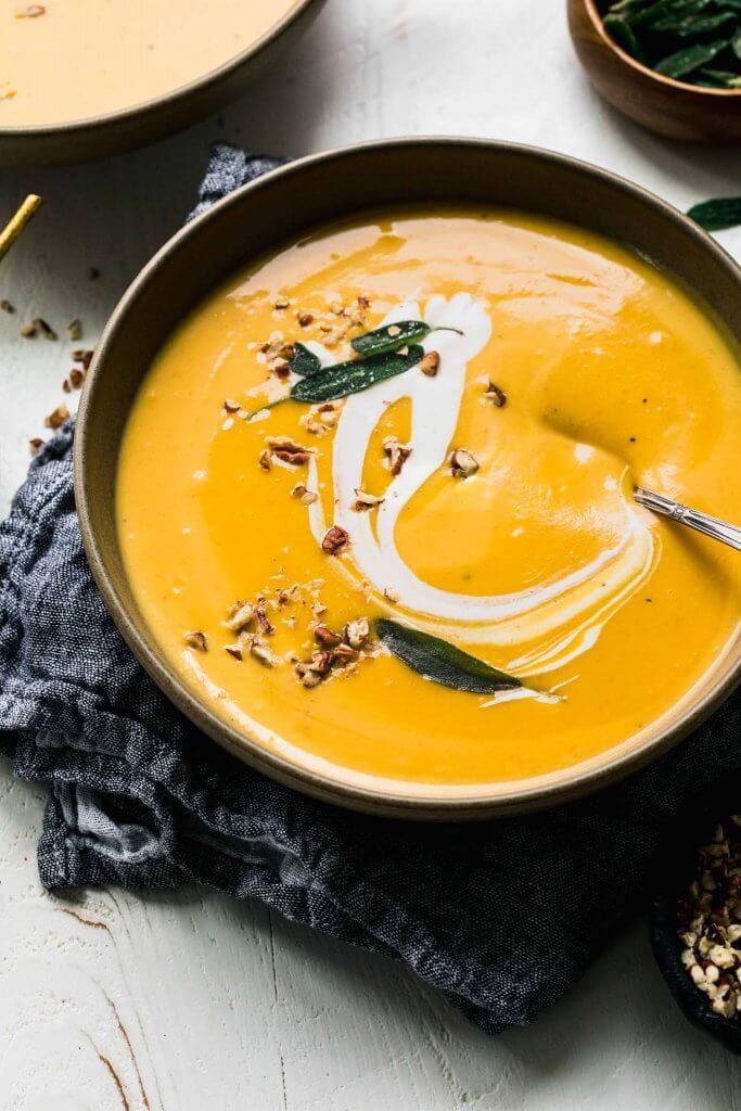 Two bowls of butternut squash bisque on counter. 