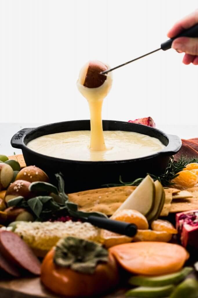 Pretzel bite being dipped into fondue.