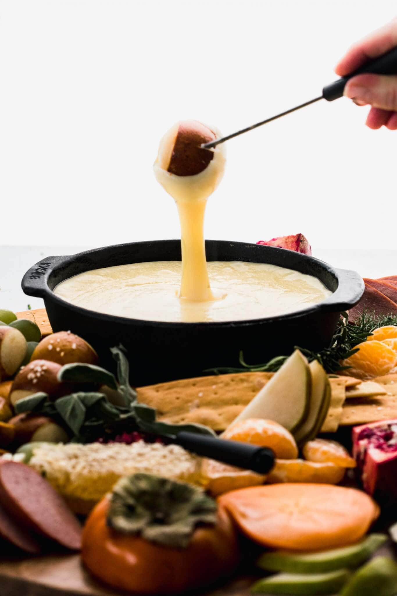 Pretzel bite being dipped into fondue. 