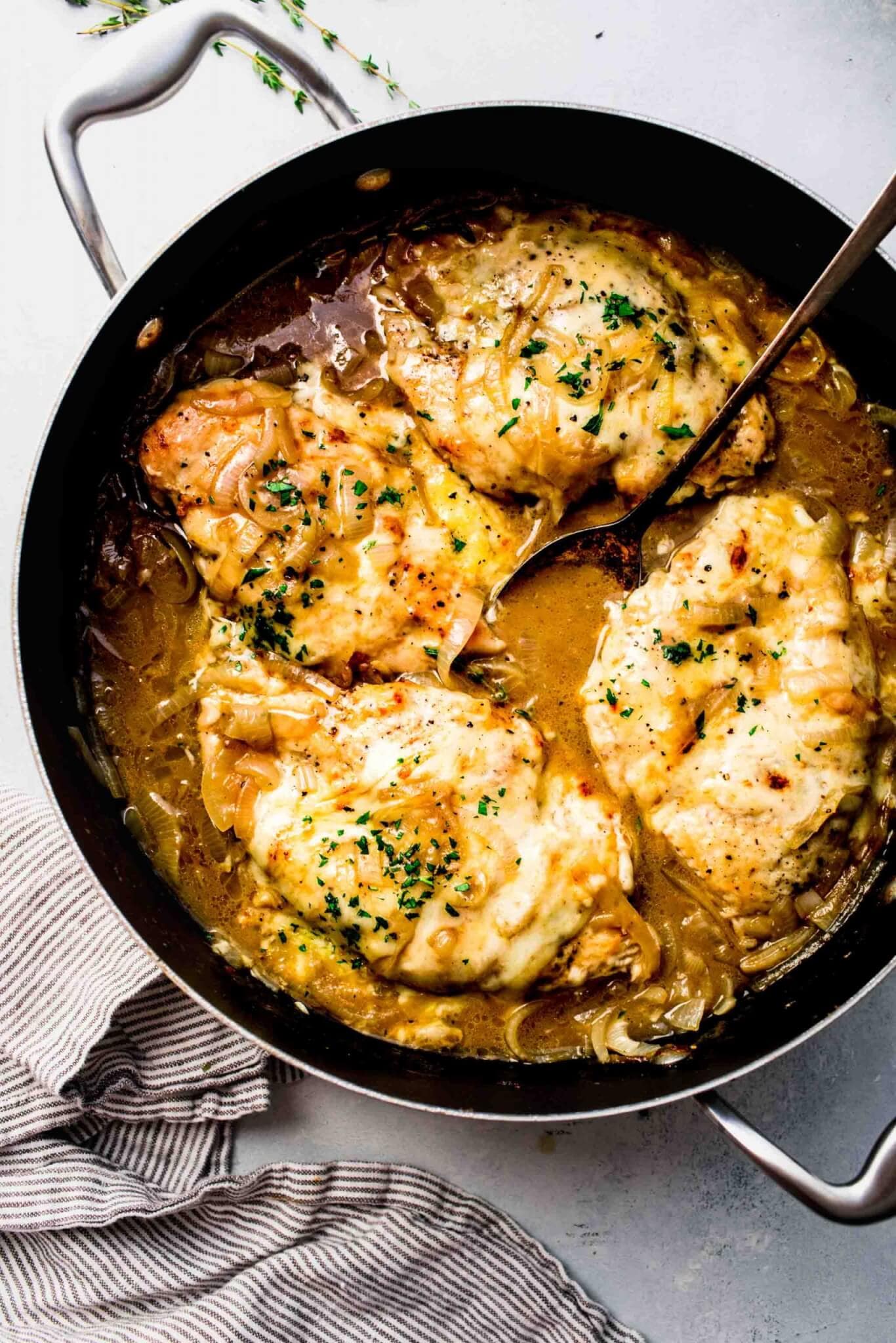 Topview of spoon scooping French Onion Chicken out of skillet. 