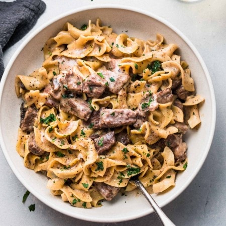Overhead shot of beef stroganoff in large white bowl with spoon.
