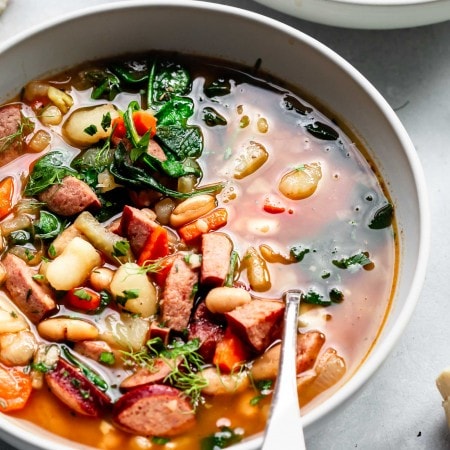 Two bowls of kielbasa soup with spoons