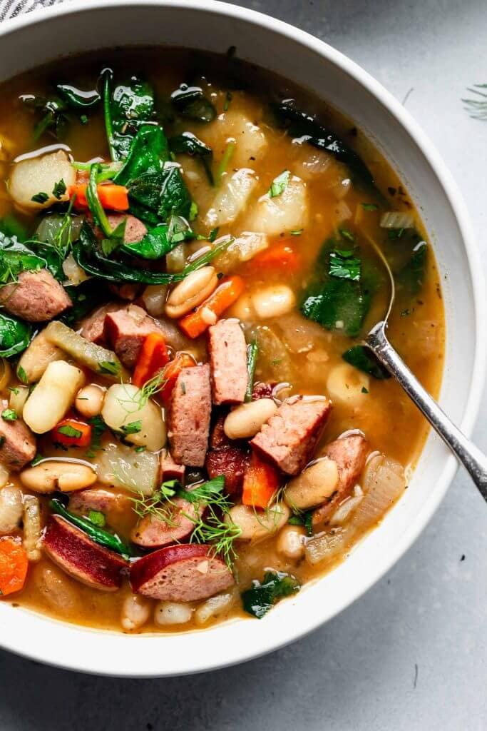 Overhead shot of bowl of kielbasa soup in white bowl.