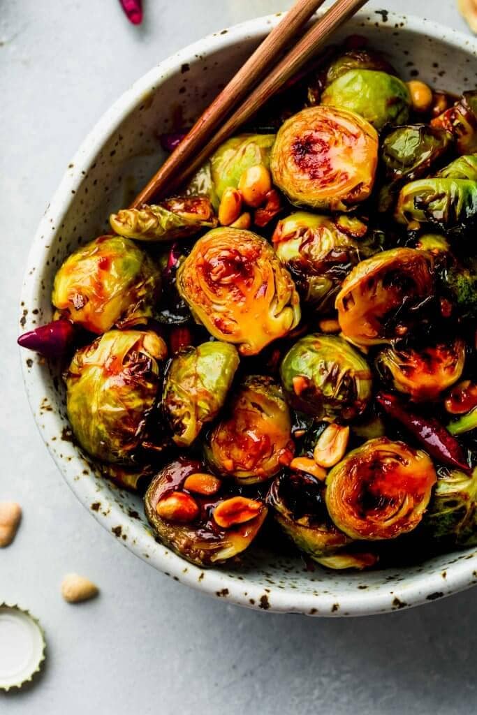 Bowl of Kung Pao Brussels Sprouts with chopsticks.