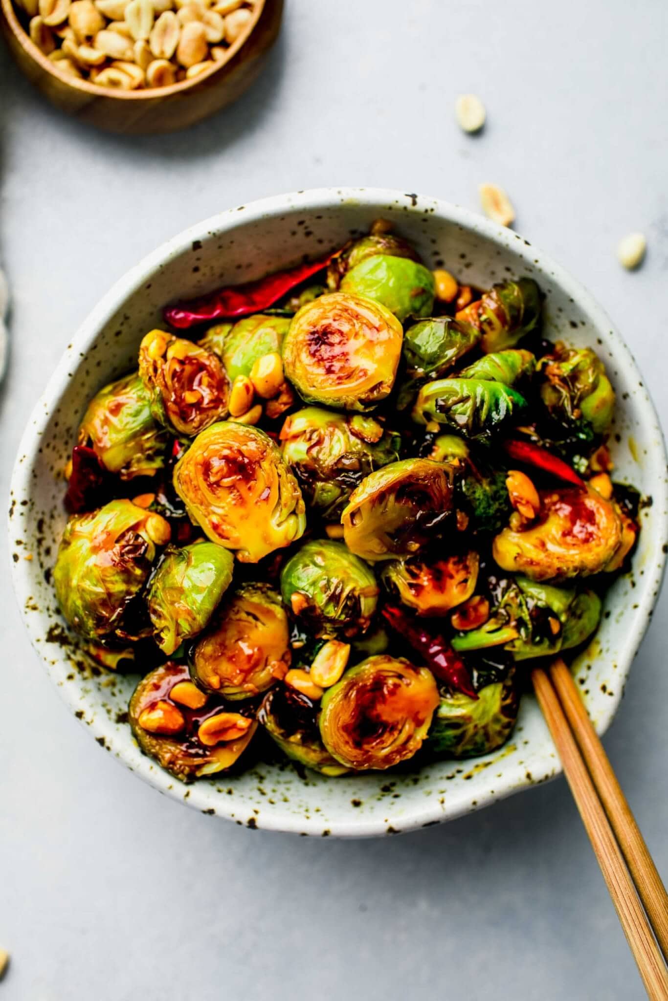 Bowl of cooked Kung Pao Brussels Sprouts with chopsticks in bowl