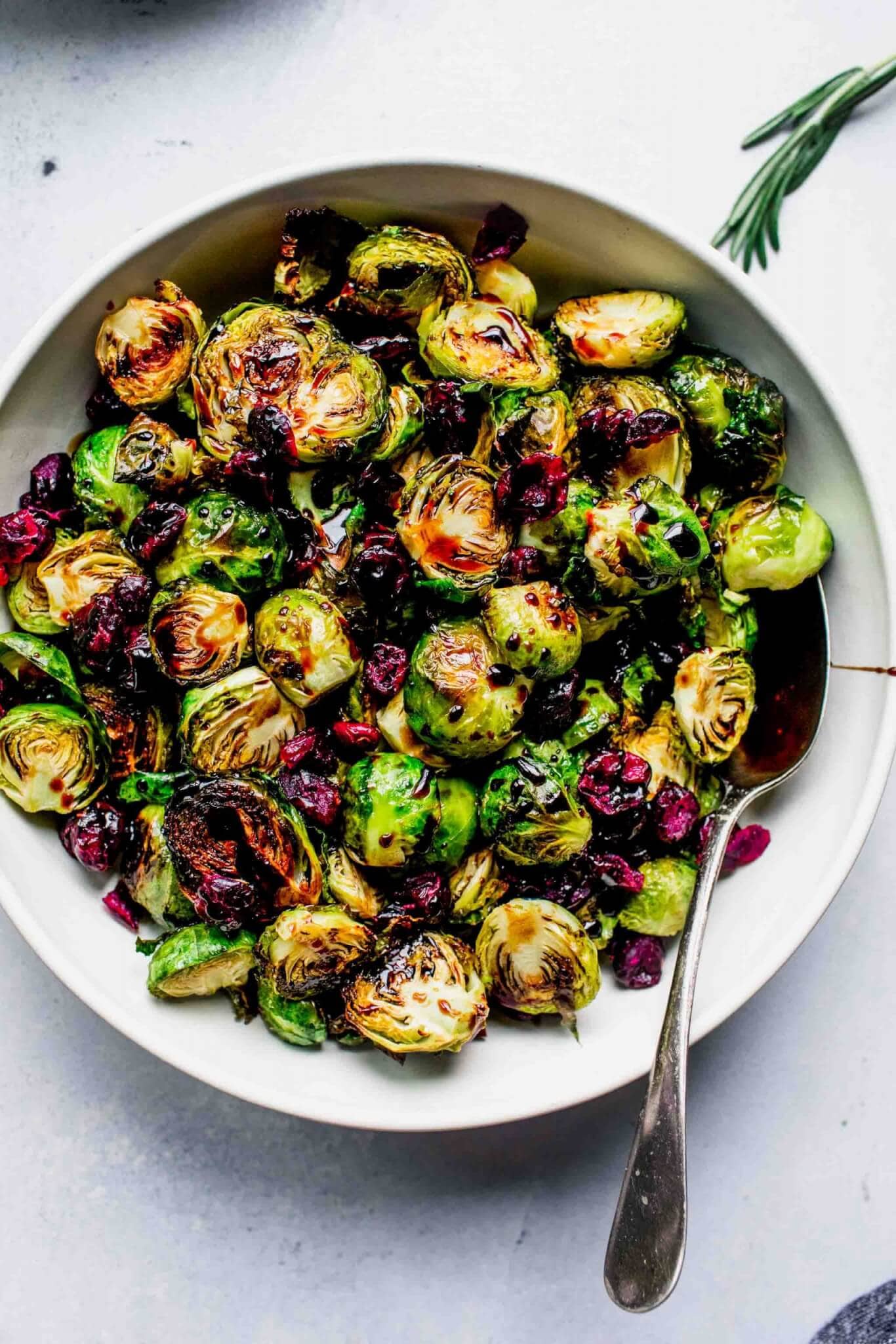 Roasted sprouts in bowl drizzled with balsamic glaze and sprinkled with cranberries.