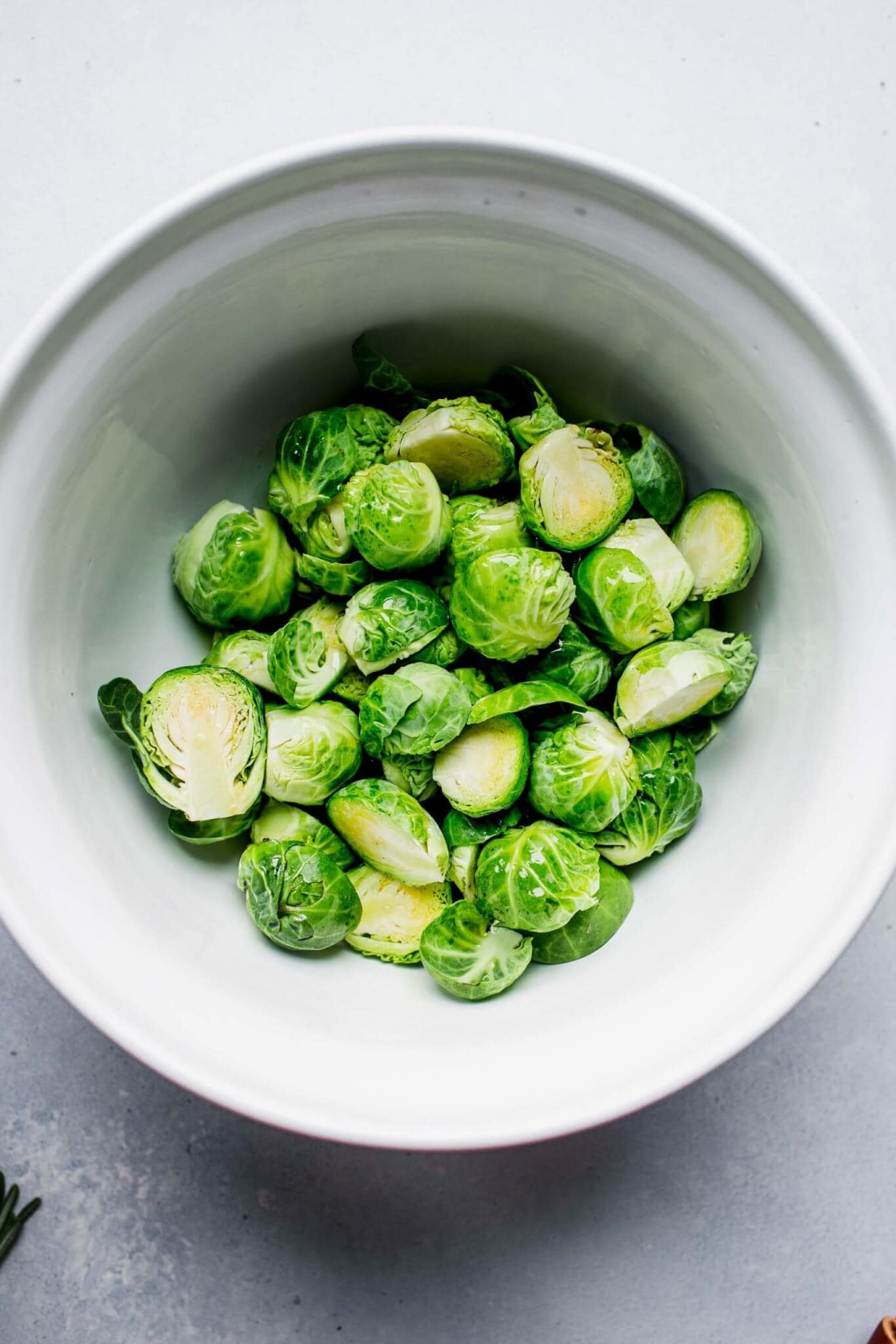 Halved brussel sprouts in white bowl.