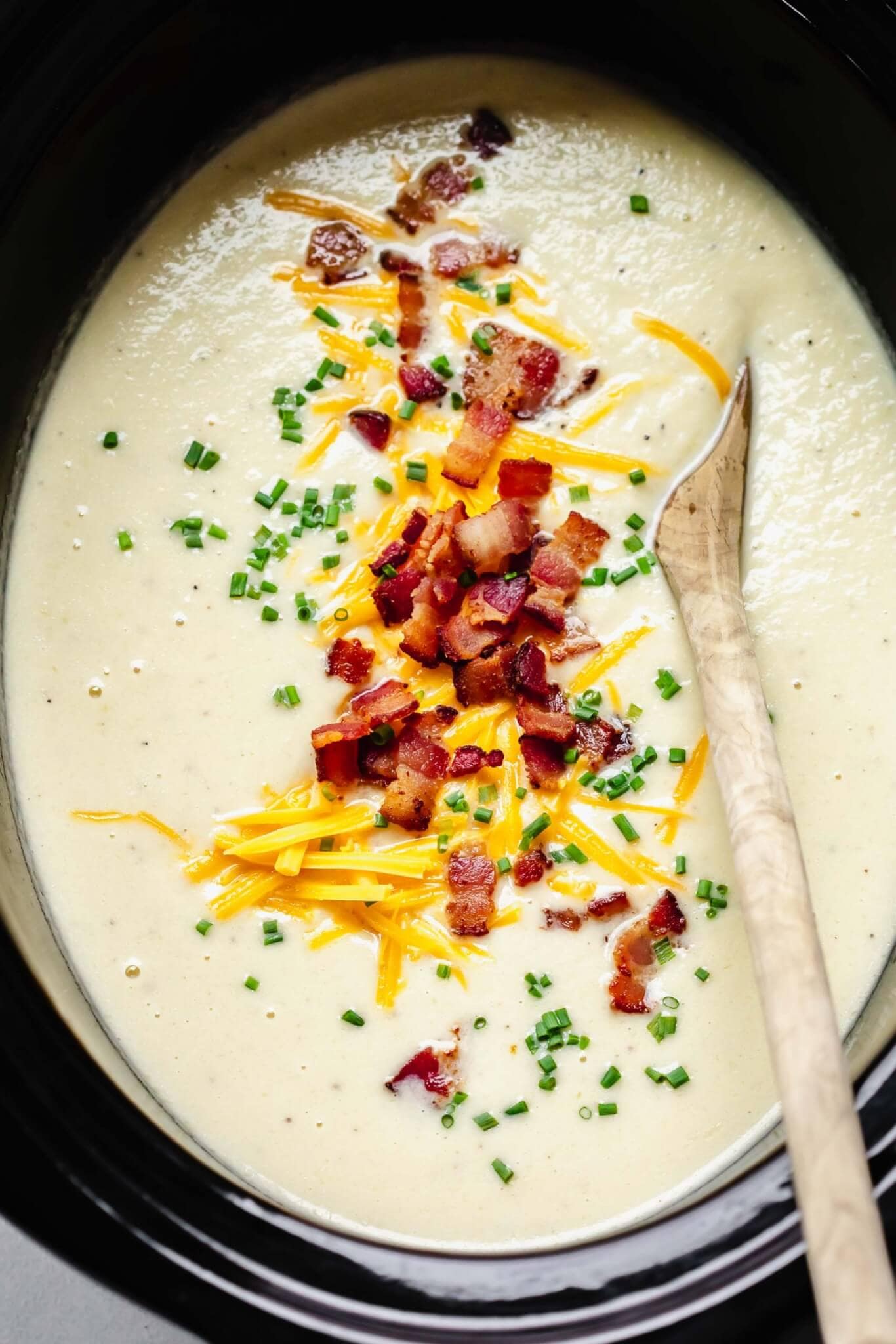 Finished cauliflower soup in crockpot with toppings.