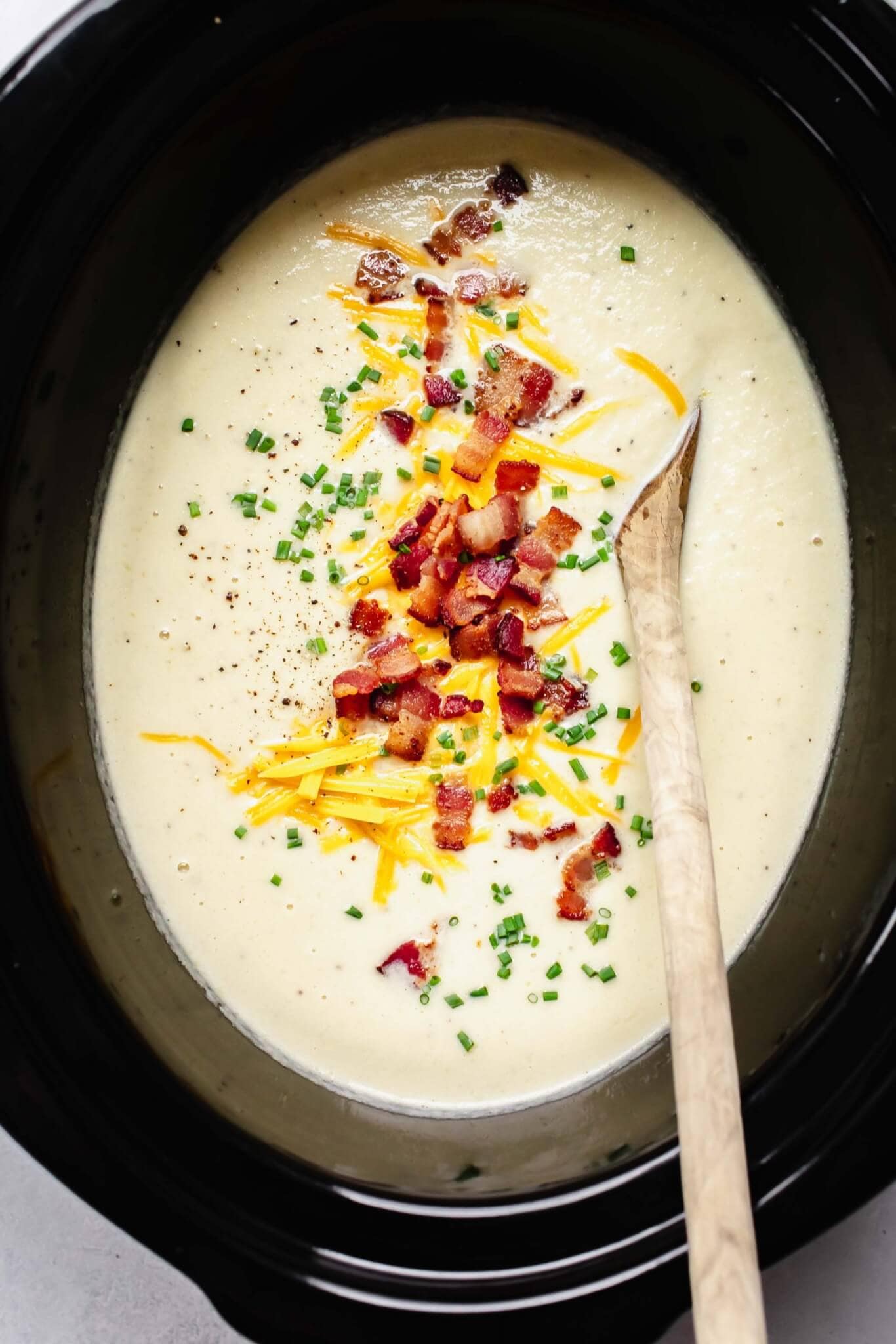 Finished cauliflower soup in crockpot with toppings.
