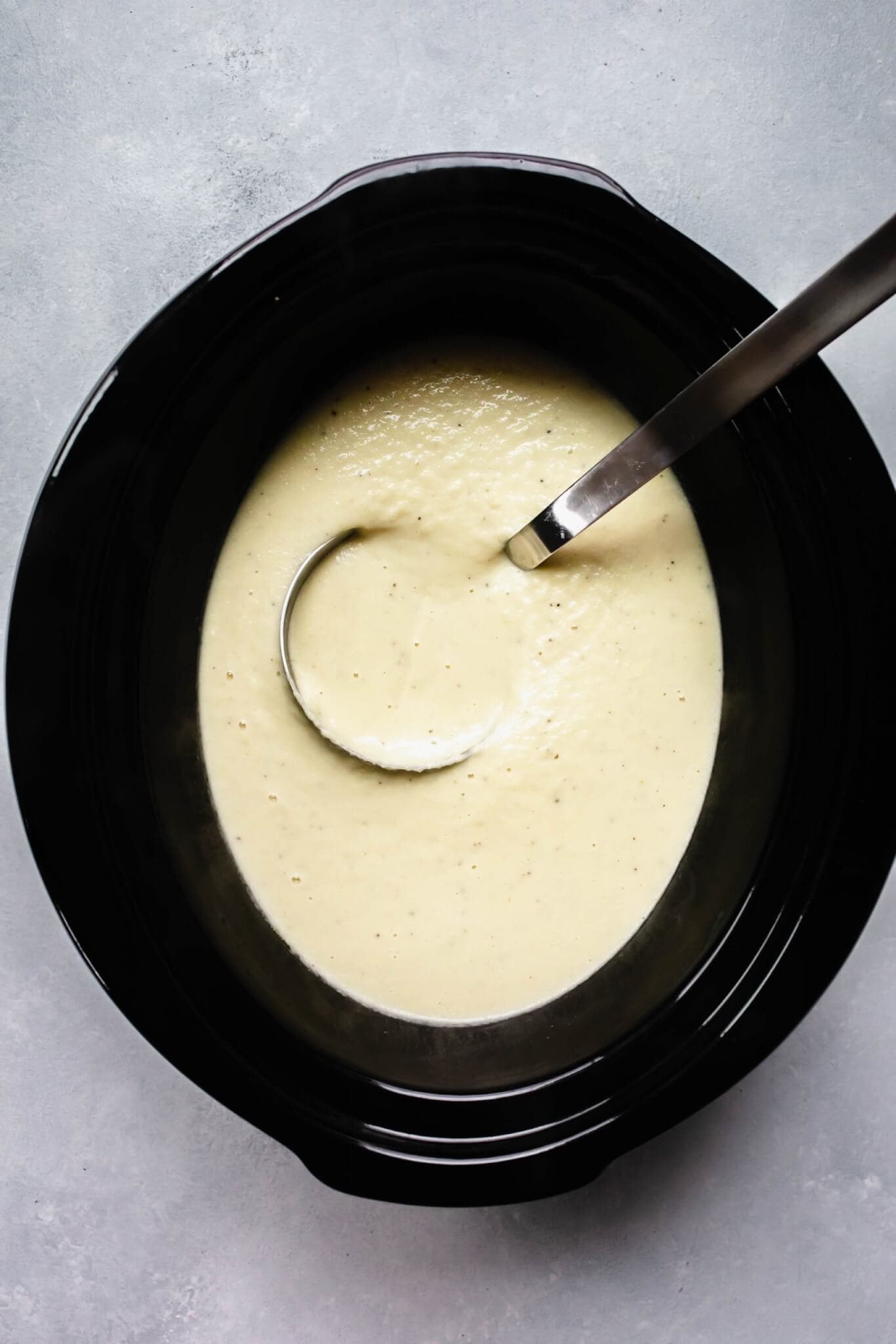 Ladle in crockpot with cauliflower soup.