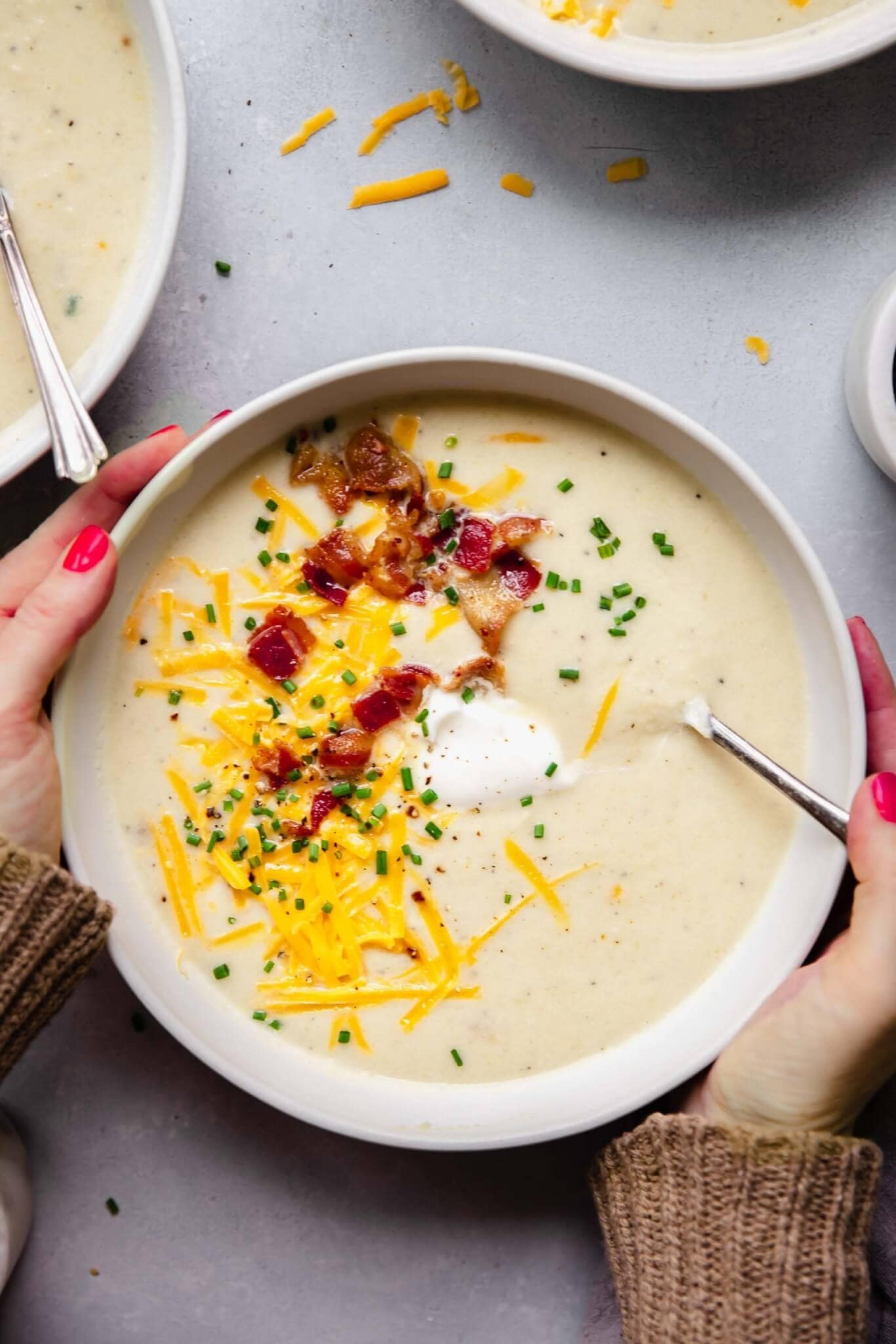 Hands holding bowl of cauliflower soup