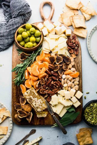 Cheese board arranged on counter with serving utensils.