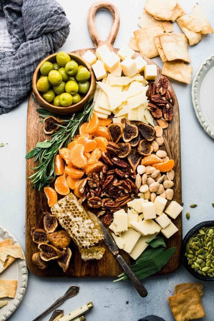 Cheese board arranged on counter with serving utensils. 