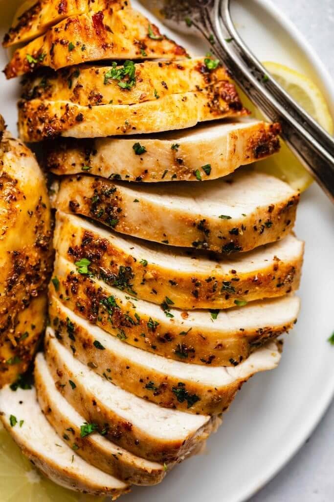 Sliced baked chicken breast arranged on plate.