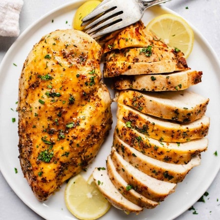 Plated chicken breasts with herbs and seasoning.