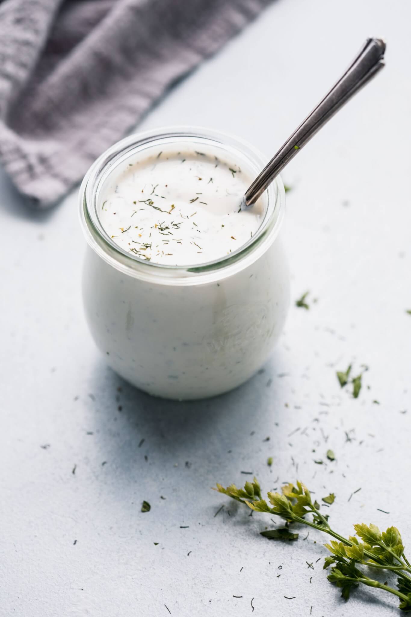 Side view of small jar of homemade ranch dressing with spoon.