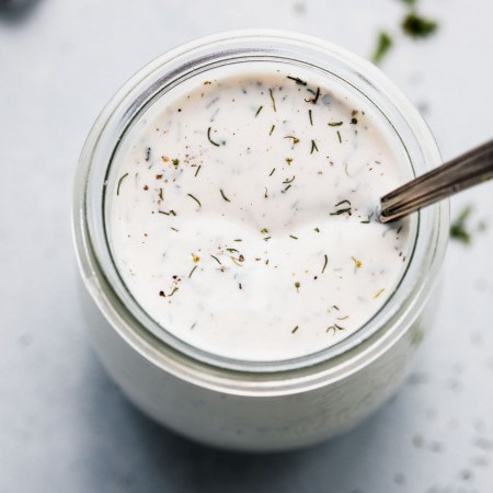 Restaurant ranch dressing in small glass jar with spoon.