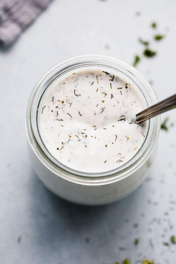 Restaurant ranch dressing in small glass jar with spoon.