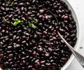 Top shot of black beans in large white bowl with spoon
