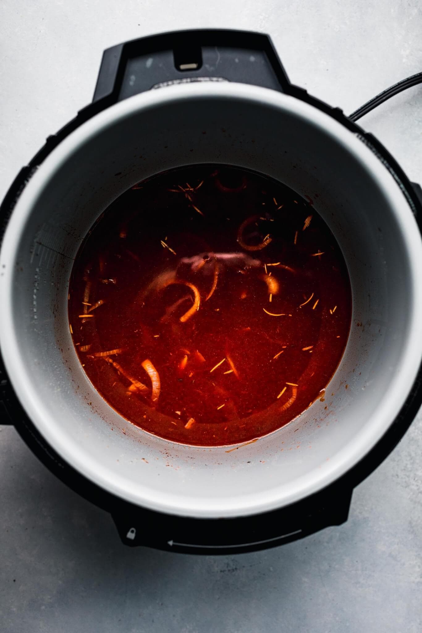 Broth and red wine added to pot