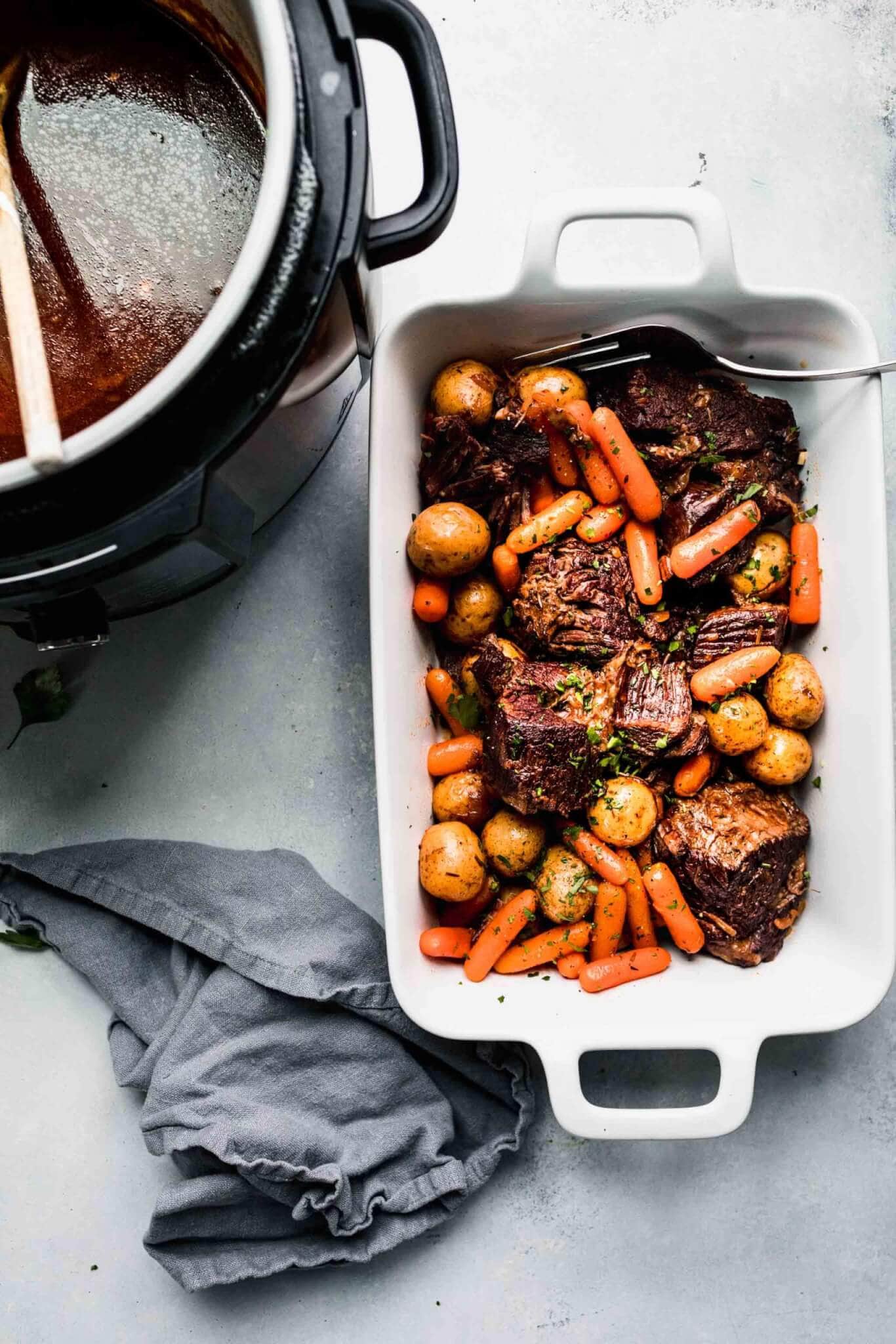 White tray with pot roast and veggies next to instant pot 