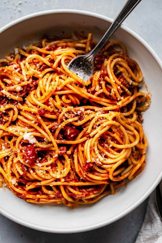 top shot of spaghetti noodles and tomato sauce in white bowl