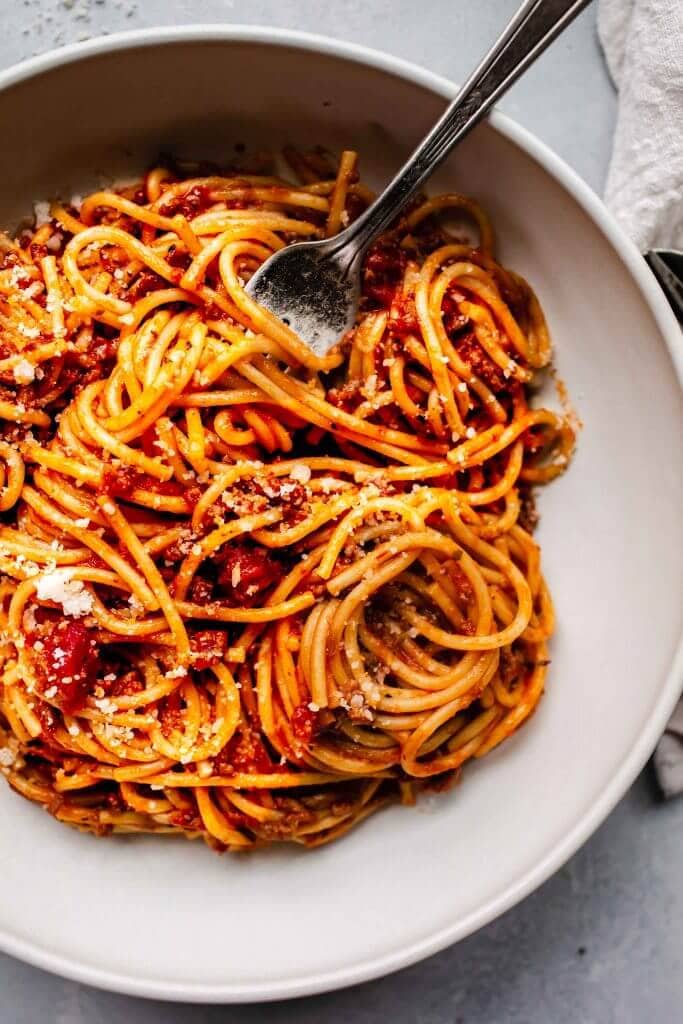 top shot of spaghetti noodles and tomato sauce in white bowl
