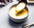 Spoon stirring lemon butter sauce in small white bowl