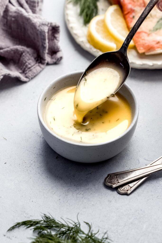 Spoon stirring lemon butter sauce in small white bowl