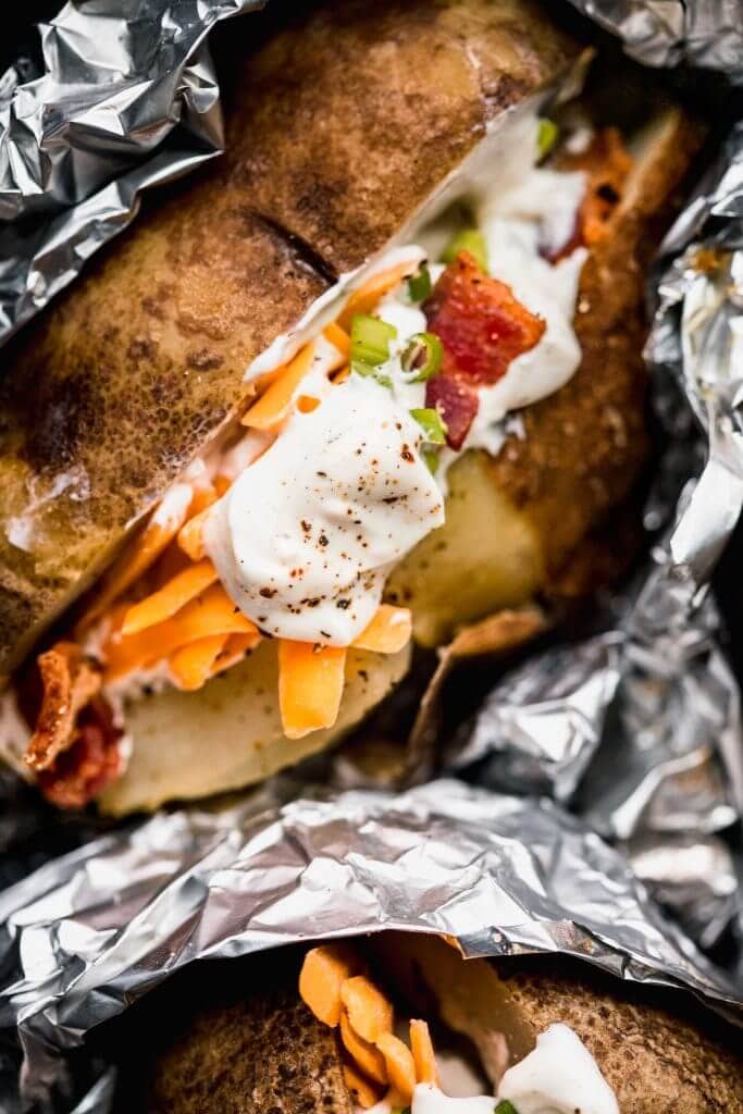 Close up of baked potato with sour cream, cheese and bacon.