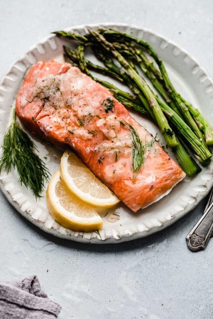 salmon with asparagus and lime wedges on white plate