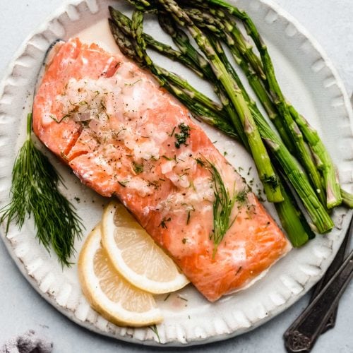 salmon with asparagus and lime wedges on white plate