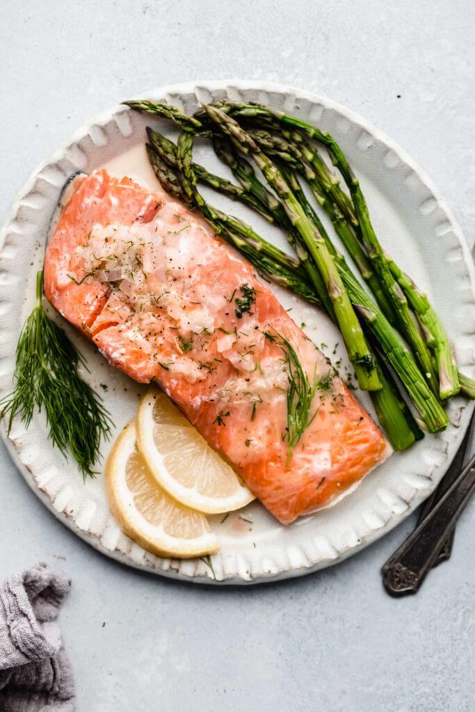 salmon with asparagus and lime wedges on white plate