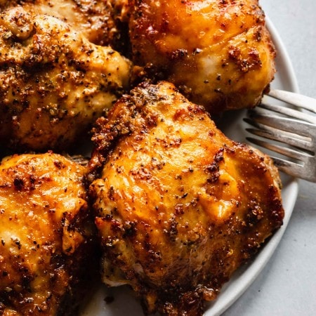 Side view of air fryer chicken thighs on plate.