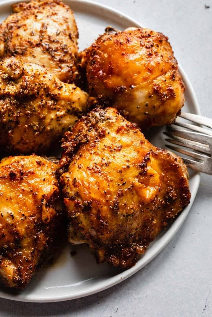 Side view of air fryer chicken thighs on plate. 