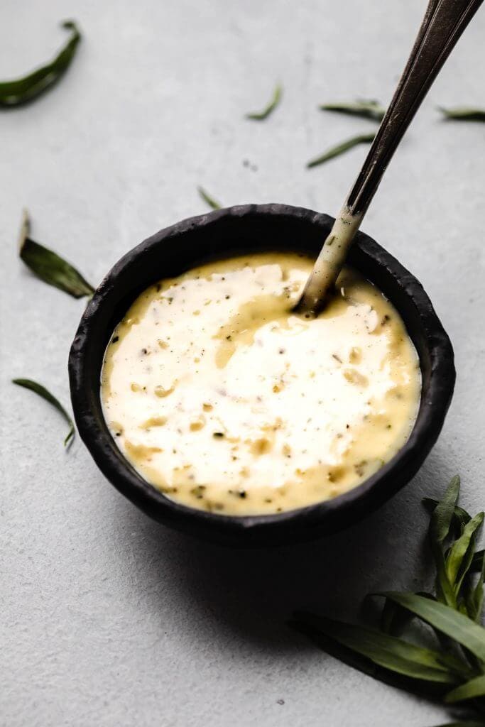 Bearnaise sauce in small black bowl. 