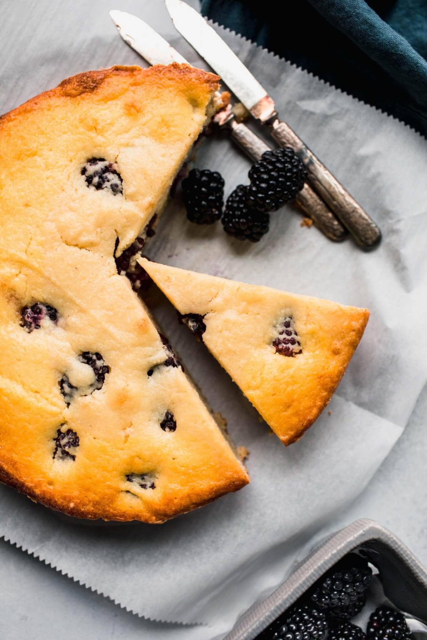 Ricotta cake cut into pieces next to blackberries.