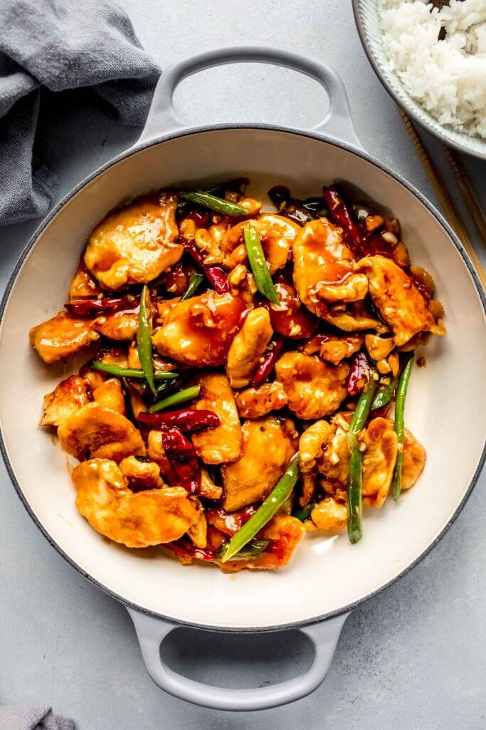 Closeup of mongolian chicken in skillet with chopsticks.