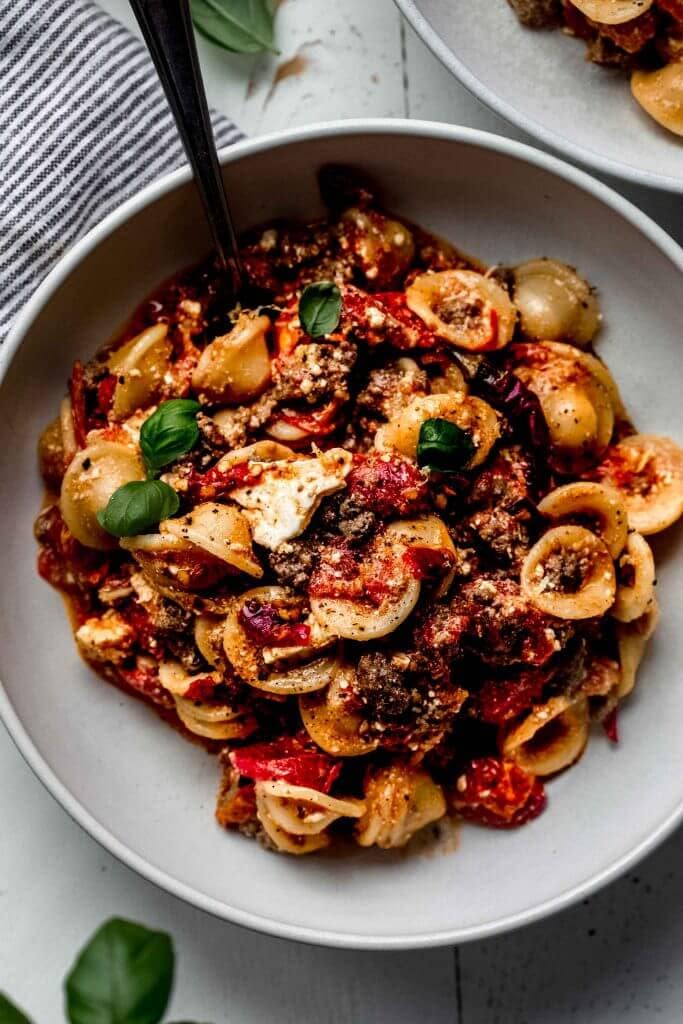 Overhead close up shot of feta pasta in shallow white bowl.