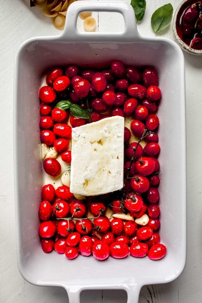 Cherry tomatoes topped with brick of feta before baking in oven.