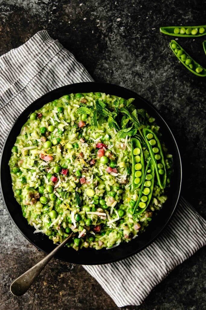 Overhead shot of pea risotto in black bowl.