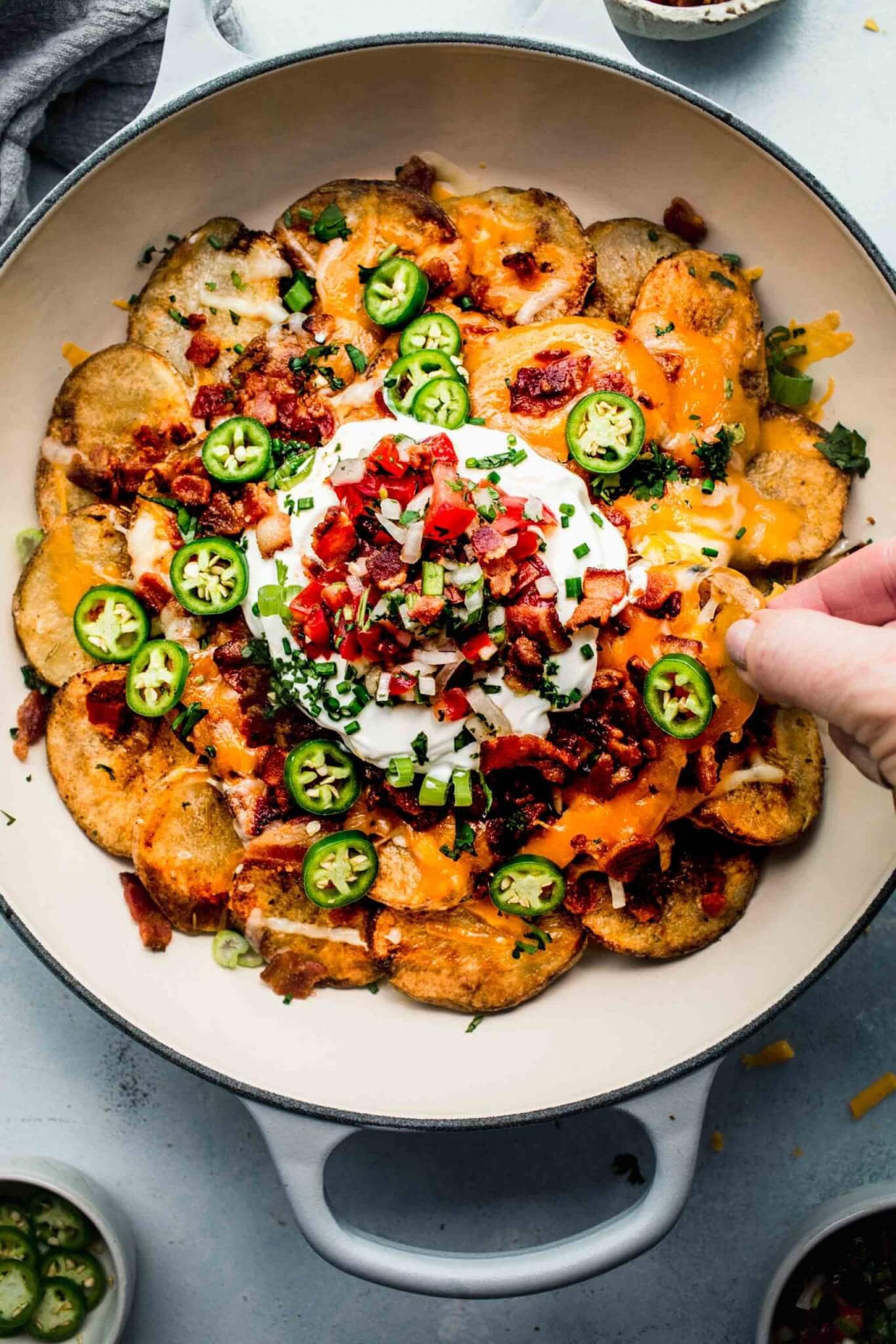 Hand reaching for irish nacho in pan.